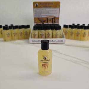 Op de afbeelding: Een display van kleine, heldere flessen Butcher Block Conditioner met zwarte doppen. De flessen zijn gevuld met een gele vloeistof en hebben een etiket met de productnaam en een afbeelding van een slagerstafel. De displaydoos is zichtbaar op de achtergrond.