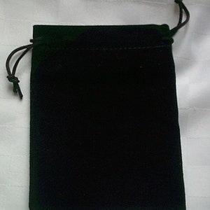 May include: A black velvet drawstring bag. The bag is rectangular with rounded corners and a drawstring closure at the top. The bag is made of a soft, plush material.