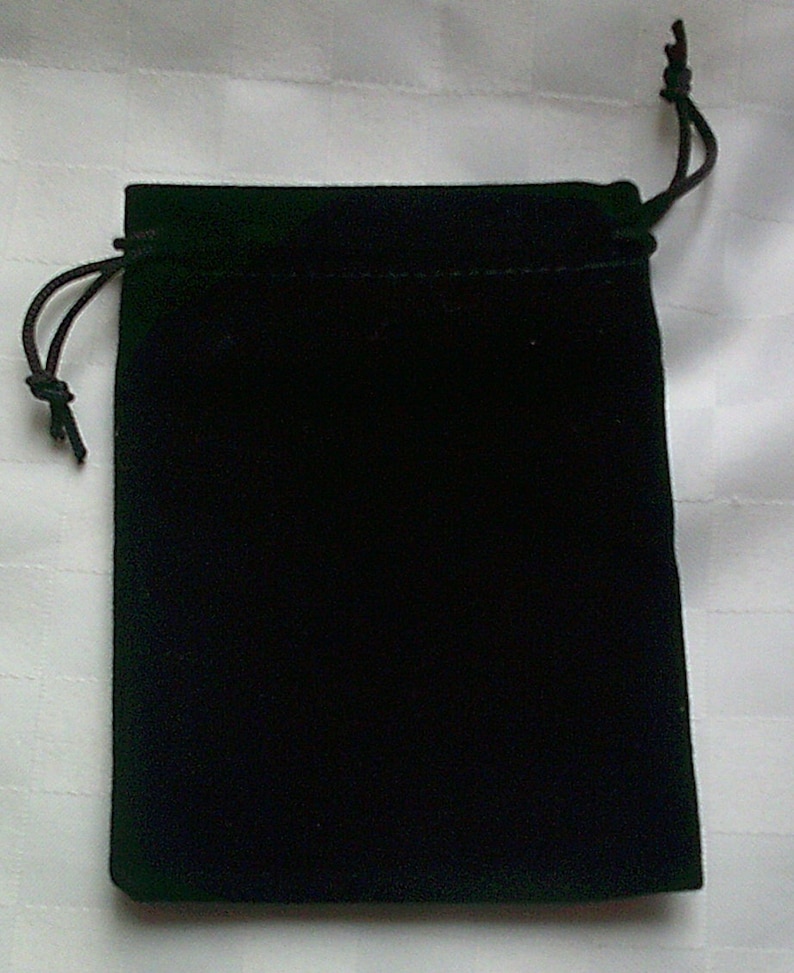 May include: A black velvet drawstring bag. The bag is rectangular with rounded corners and a drawstring closure at the top. The bag is made of a soft, plush material.