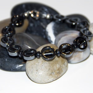 Circular and Tube Hematite 14mm with Magnetic Hematite 6mm Disc. Fastens with a .925 Sterling Silver Lobster Claw Clasp.