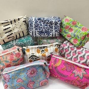 Puede incluir: Una colección de estuches rectangulares de tela acolchada con varios patrones florales y geométricos estampados en bloque en colores vibrantes como rosa, azul, verde, amarillo y crema, cada uno con cierre de cremallera superior.