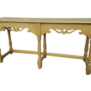 May include: A light wood console table with a carved design on the underside of the top and turned legs.