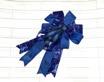 May include: Blue and black glitter bow with the text "Peace Maker", "Brave", "Thank you", "Love", "Strong", "Enforcers", "Police", "Blue", "Protect & Serve", "Hero" on the ribbon.