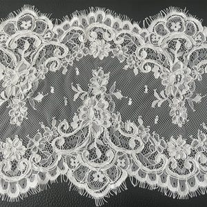 Peut inclure: Dentelle blanche avec un motif floral et de feuilles. La dentelle présente un bord festonné et des détails complexes. Cette garniture délicate convient à divers projets d'artisanat et de couture.