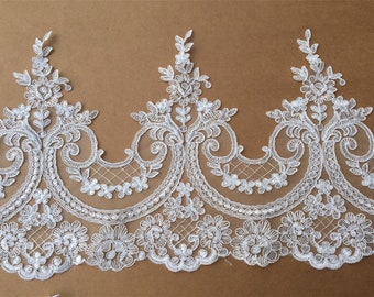 May include: White lace trim with a floral design and sequins. The lace has a scalloped edge.