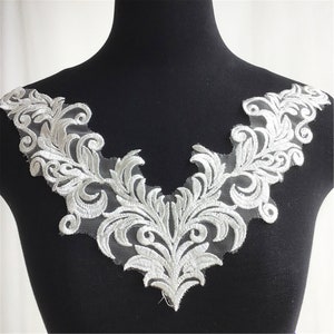 Puede incluir: Aplique de encaje blanco con un diseño floral. El encaje es delicado e intrincado, con un borde festoneado. Este aplique es perfecto para agregar un toque de elegancia a cualquier proyecto.