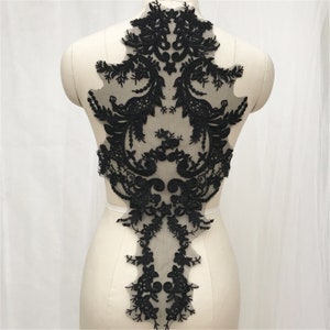 May include: Black lace applique with a delicate floral design. The applique is perfect for adding a touch of elegance to any garment.