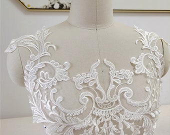 Può includere: Applique in pizzo bianco con un delicato motivo floreale. Il pizzo è perfetto per aggiungere un tocco di eleganza a qualsiasi capo.