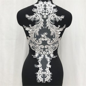 May include: White lace applique with a floral design. The applique is on a black background and is about 12 inches tall.