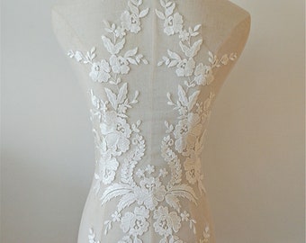 May include: White floral lace applique with delicate flowers and leaves. This lace applique is perfect for adding a touch of elegance to any garment or project.