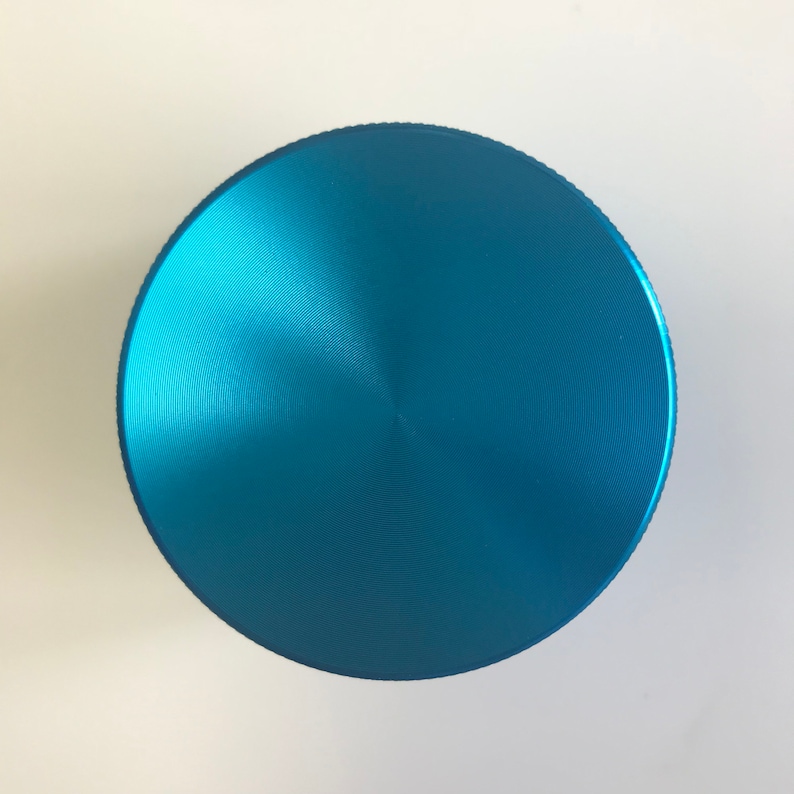 Puede incluir: Un molinillo redondo de metal azul con un acabado liso cepillado.