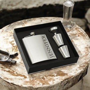 May include: A silver flask engraved with the name "Jennifer", in a black gift box with two silver shot glasses and a funnel.