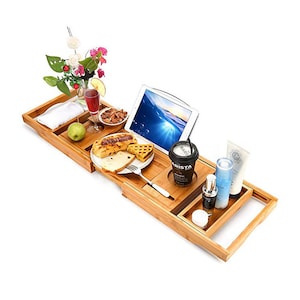 Peut inclure: Un plateau de bain en bambou avec un porte-livre intégré, un porte-gobelet et un petit plateau pour les collations. Le plateau est rempli de divers articles, dont un verre de vin, une assiette de nourriture, un livre et une tasse de café.