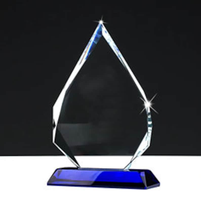 May include: A clear glass award with a blue base. The award is shaped like a teardrop and has a faceted design.