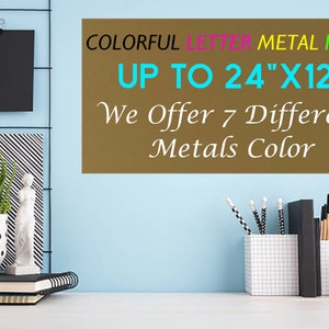 May include: A rectangular brown metal plate with the text COLORFUL LETTER METAL PLATE UP TO 24"X12" We Offer 7 Different Metals Color. The plate is displayed against a light blue wall with a desk containing a potted plant, books, and office supplies.