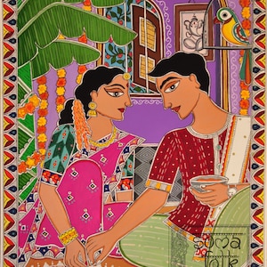 May include: A traditional Indian folk art painting depicting a couple in a colorful setting. The woman is wearing a pink sari and is drawing a rangoli design on the floor. The man is wearing a red shirt and white dhoti and is holding a cup. The painting is framed with a decorative border.