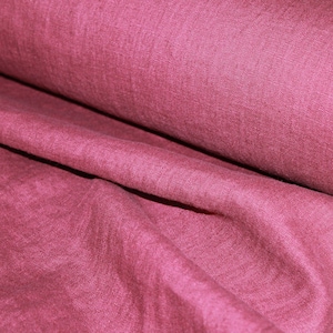 Könnte beinhalten: Eine Stoffrolle in einem tiefen Rosaton. Der Stoff ist dicht gewebt mit einer leicht strukturierten Oberfläche. Die Rolle ist teilweise abgerollt und zeigt den weichen Fall des Stoffes. Ideal für Nähprojekte.