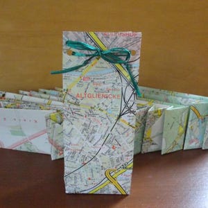 Könnte beinhalten: Ein Set kleiner Geschenktüten aus Karten von Berlin, Deutschland. Die Taschen sind mit einem grünen Band und einer Schleife verziert. Der Text auf der Karte lautet "ALTGLIENICKE".