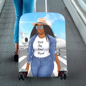 May include: A luggage cover featuring a cartoon illustration of a woman wearing a denim jacket, sunglasses, and a hat. The woman is standing in front of a private jet with the text "Work Slay Travel Repeat" on her shirt. The luggage cover is blue and white.