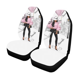 May include: Two black and white car seat covers with a pink and white illustration of a woman in a pink top, black pants, and a white hat. The illustration includes a hot air balloon and the text "Amanda".