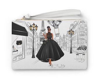 May include: A white clutch bag with a black and white illustration of a woman in a black dress walking in Paris. The Eiffel Tower and a hot air balloon are in the background.