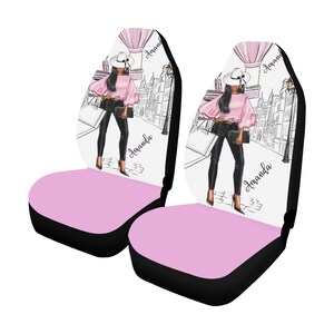 May include: Two pink and black car seat covers with a white background featuring a woman in a pink top, black pants, and a white hat. The woman is walking down a street with a hot air balloon in the background. The text "Amanda" is written on each cover.