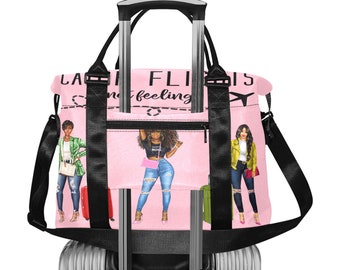 May include: Pink travel bag with black straps and a silver handle. The bag features illustrations of stylish women and the text "LAZY FLIGHTS, I'M NOT FEELING IT". The bag is on top of a silver rolling suitcase.
