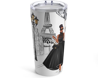 May include: A white travel mug with a black and white illustration of a woman in a black dress walking in front of the Eiffel Tower in Paris. The text "Pâtisserie" is visible on a building in the background.