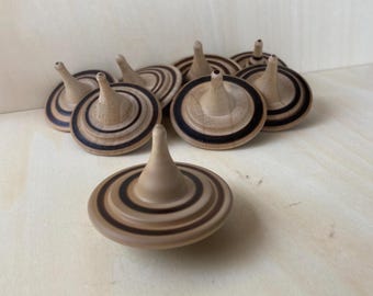 May include: A group of wooden spinning tops with black and brown stripes. The tops are made of light wood and have a pointed tip.