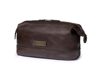 May include: A brown leather travel toiletry bag with a zipper closure and a brass nameplate that reads "LUKAS ENSBERG".