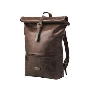 Puede incluir: Una mochila de cuero marrón con cierre enrollable y correa con hebilla. La mochila tiene un bolsillo frontal con cremallera y correas ajustables. El cuero tiene un aspecto envejecido.