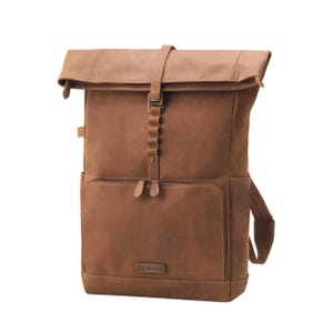 May include: A brown leather backpack with a roll-top closure and a front pocket. The backpack features a buckle closure and adjustable straps. The bag has a rectangular shape and a small rectangular metal tag on the front.