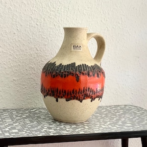 May include: A set of three ceramic mugs with a speckled, matte finish. The mugs are in shades of cream, light gray, and dark gray. Each mug has a simple, minimalist design and a rounded handle. The mugs are stacked on top of each other.