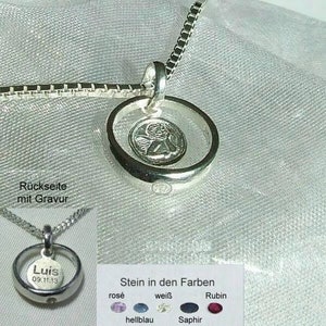 Könnte beinhalten: Silberkette mit einem runden Anhänger mit einem Engelsmotiv. Der Anhänger hat eine klare Mitte und einen silbernen Ring am Rand. Die Rückseite des Anhängers kann mit einem Namen und Datum graviert werden. Die Kette wird mit einer Auswahl an farbigen Edelsteinen geliefert: rosa, weiß, blau oder rot.