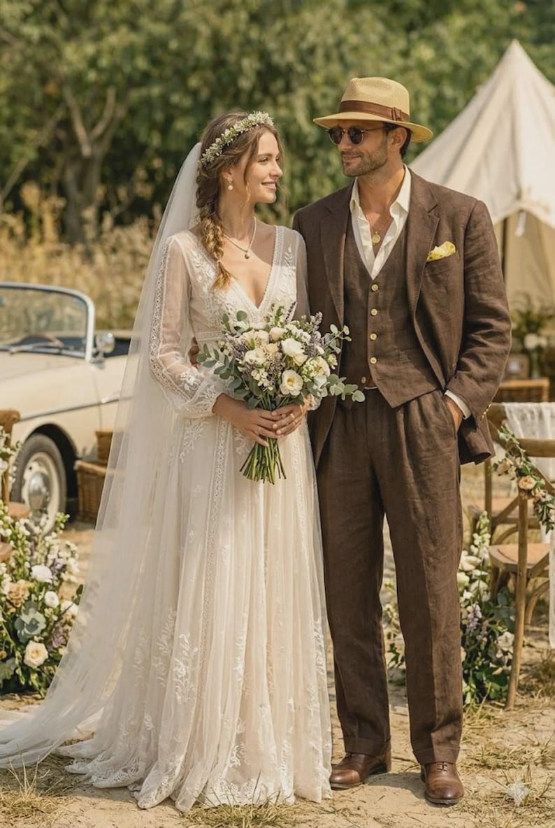 Puede incluir: Una pareja vestida para una boda al aire libre. La persona de la izquierda lleva un vestido de novia de encaje blanco con velo largo y sostiene un ramo. La persona de la derecha lleva un traje y sombrero marrones. Un coche antiguo y una tienda de campa&ntilde;a est&aacute;n al fondo.