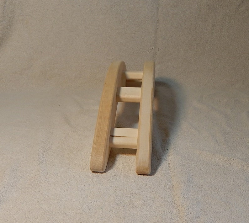 Puede incluir: Un arco de madera con tres listones horizontales, dise&ntilde;ado para que los animales peque&ntilde;os puedan trepar por encima. El arco est&aacute; hecho de madera natural y tiene un color marr&oacute;n claro.