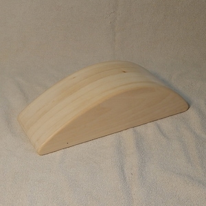 May include: A light brown wooden half-cylinder shaped bolster for yoga or exercise.