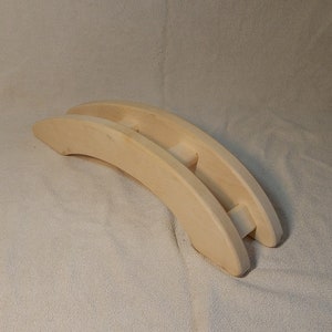 Puede incluir: Un juguete de madera en forma de puente, hecho de madera natural, con un dise&ntilde;o simple. El puente es curvo y tiene dos arcos.