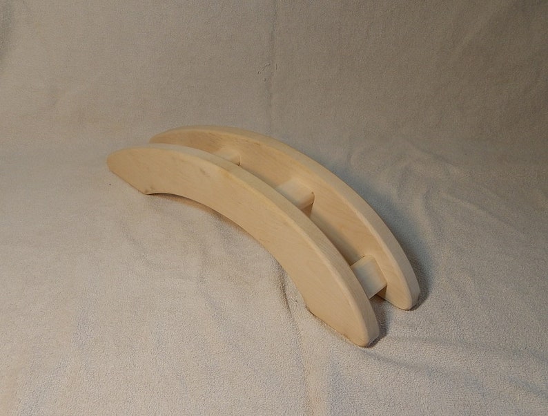 Puede incluir: Un juguete de madera en forma de puente, hecho de madera natural, con un dise&ntilde;o simple. El puente es curvo y tiene dos arcos.