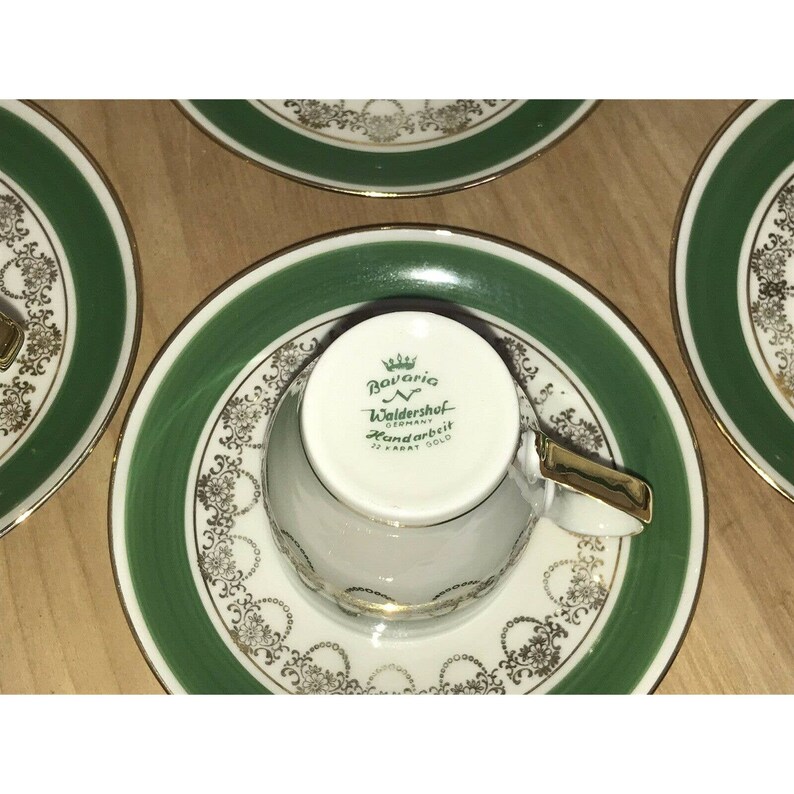 Puede incluir: Una taza de t&eacute; y un platillo de porcelana blanca con un borde verde y dorado. La taza tiene un logotipo verde y dorado que dice "Bavaria Waldershof Germany Handarbeit 22 Karat Gold".