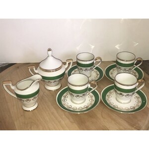 Puede incluir: Un juego de t&eacute; blanco con ribetes verdes y dorados. El juego incluye una jarra de crema, un azucarero y cuatro tazas y platillos.