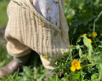 May include: Beige baby pants with a green top and a floral print pocket. The pants have a button closure and are made of a soft, textured fabric.