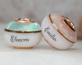 Breastmilk jewelry bead with Birth color, name, opal flakes and baby hair. 925 sterling silver cores, rose and yellow gold plating. Keepsake