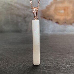 Breastmilk jewelry vertical long bar stick with opal effect flakes and rose gold plated sterling silver chain. Keepsakemom