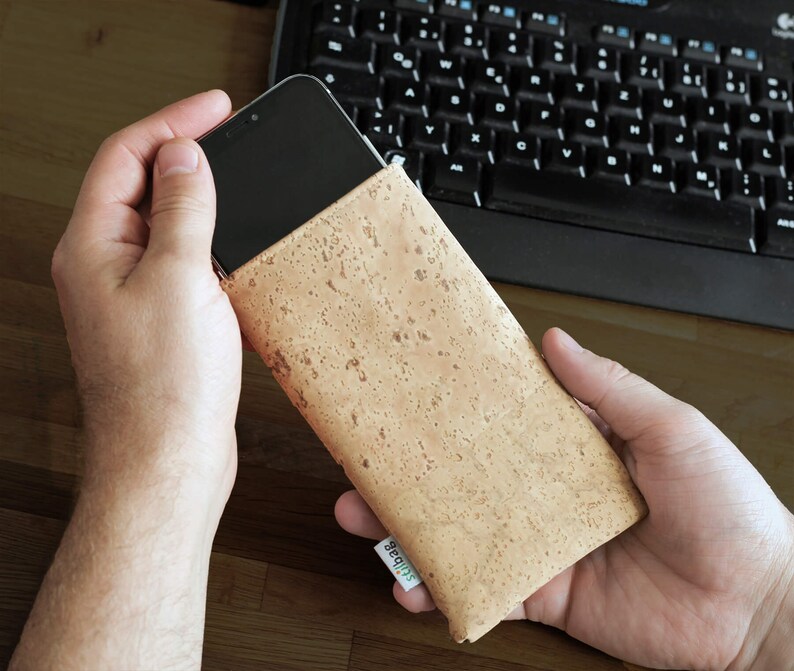 Puede incluir: Una funda de tel&eacute;fono de corcho marr&oacute;n con un logotipo verde "Slubber". La funda est&aacute; hecha de corcho natural y tiene una superficie texturizada.