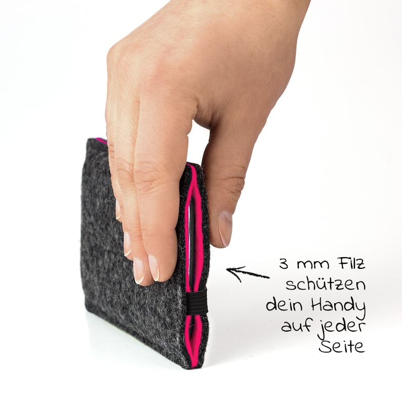 May include: A gray felt phone case with pink edging. The case is 3 mm thick and protects your phone on every side. The text "3 mm Filz sch&uuml;tzen dein Handy auf jeder Seite" is written in black marker on a white background.
