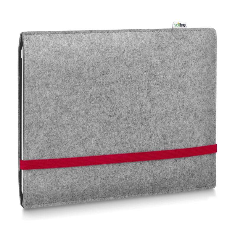 May include: A rectangular light gray felt sleeve for a tablet or laptop, featuring a horizontal bright red elastic band across the front and a small white fabric tag with the text stilbag attached to the top edge of the gray felt material.