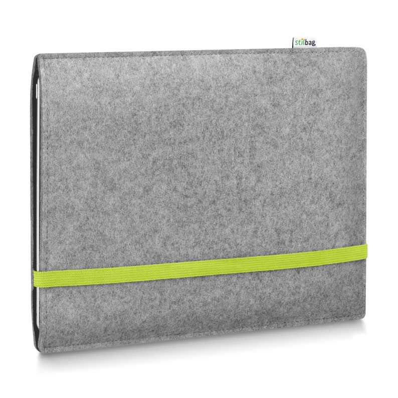 May include: A rectangular gray felt sleeve for a tablet or laptop, featuring a bright lime green elastic band wrapped horizontally around the center to secure the closure. A small white fabric tag with the text stilbag is attached to the top edge.
