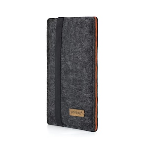 May include: A dark gray felt case with an orange trim and a black elastic band closure. The case has a small rectangular label with the word "stilbag" on it. The case is designed to hold a phone or tablet.