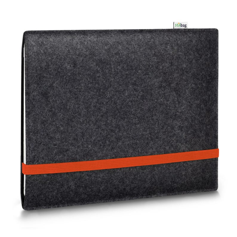 May include: A dark gray felt laptop sleeve featuring a vibrant orange elastic band wrapped horizontally around the center. A small white fabric tag with the text stilbag is attached to the top edge of the rectangular protective case.
